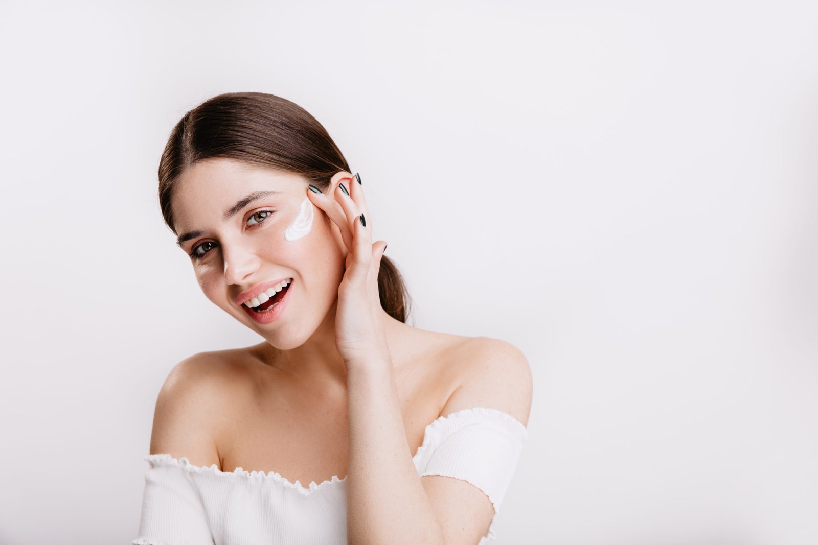 Mujer sonriente aplicando tratamiento facial